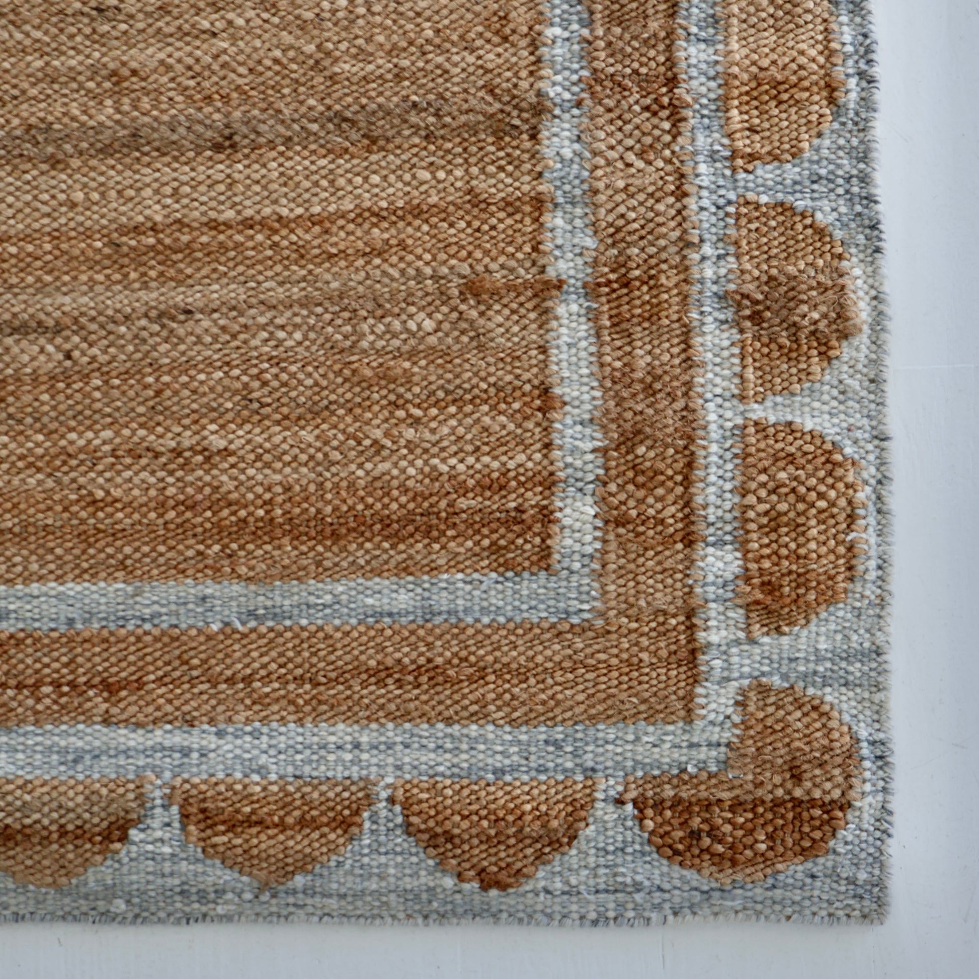 Handwoven jute and wool rug in natural tones with a stone-blue scalloped border – Stone Blue Scalloped Edge Rug by Locust Lane Rugs