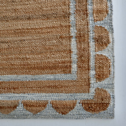 Handwoven jute and wool rug in natural tones with a stone-blue scalloped border – Stone Blue Scalloped Edge Rug by Locust Lane Rugs